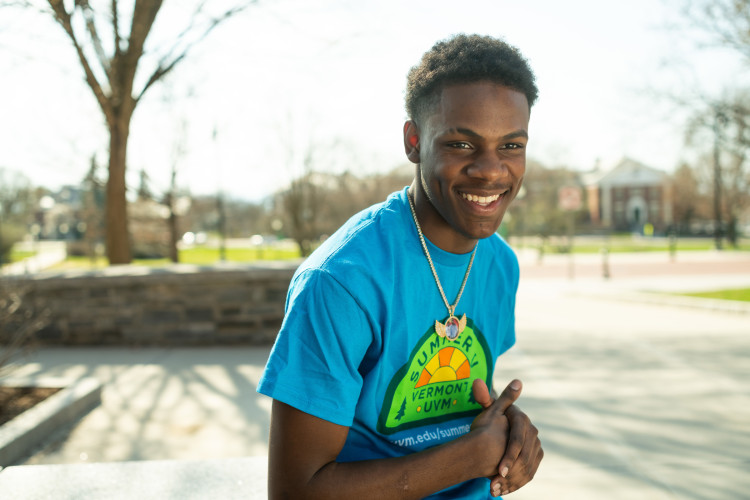 precollege student Alonzo in blue t-shirt smiling on campus