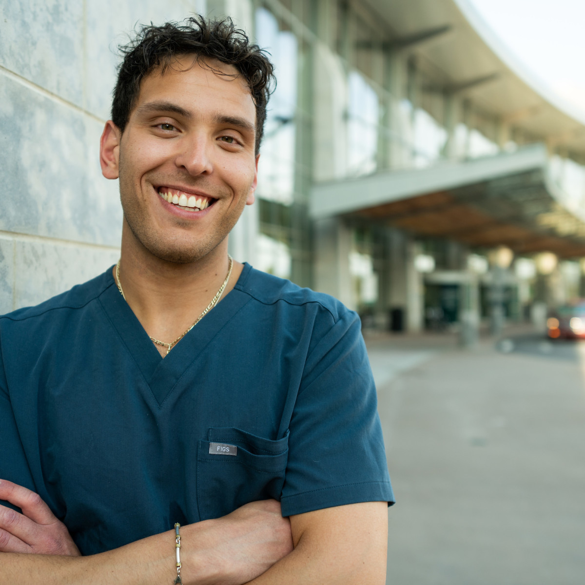 student smiling crossed arms in front of hospital