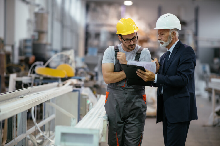 two men reviewing documents on manufacturing floor.